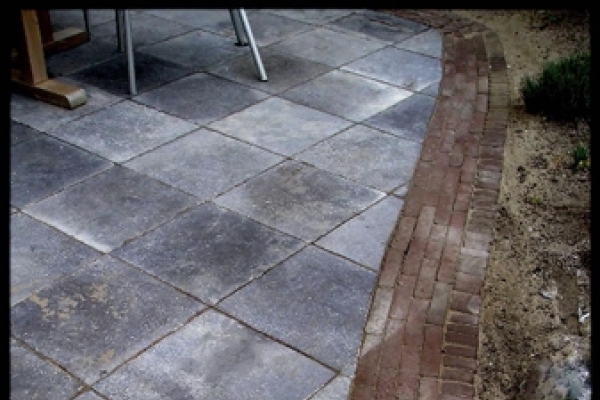 Detail van terras van natuurstenen tegels met rand van gebakken walen in Overveen